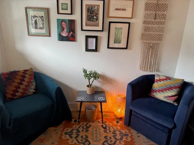 The counselling room: two armchairs, a small table with a lamp and plant, and a patterned rug