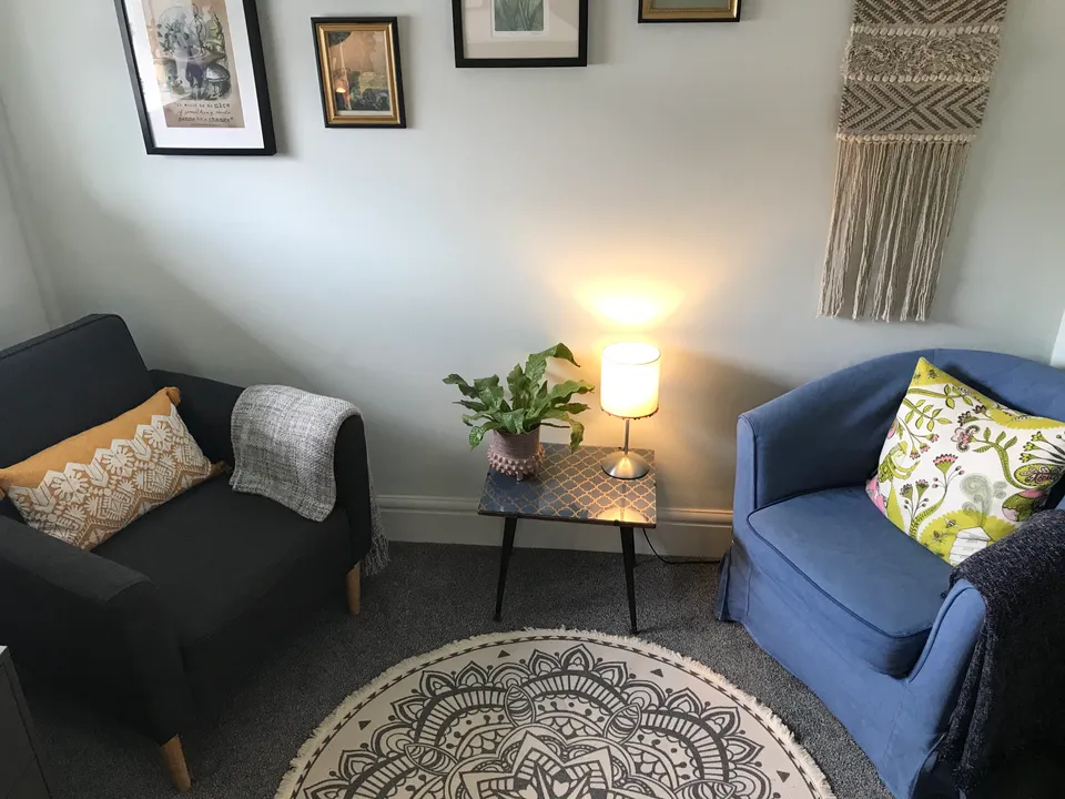 The counselling room: two armchairs, a small table with a lamp and plant, and a patterned rug