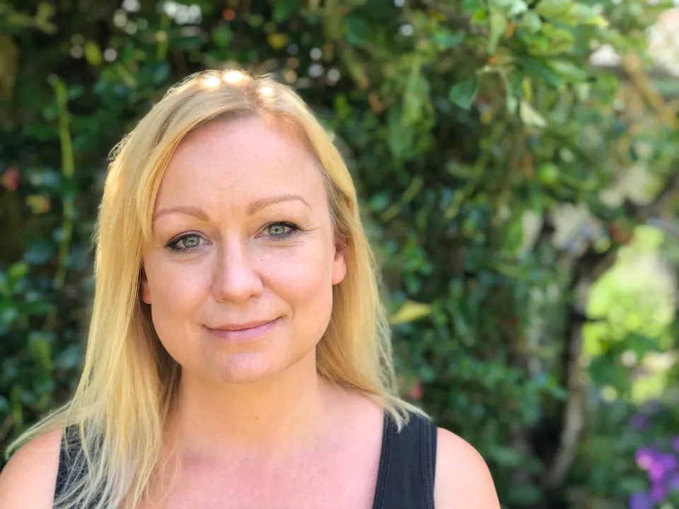 Gabbie Cailes, counsellor, photographed outdoors among green foliage